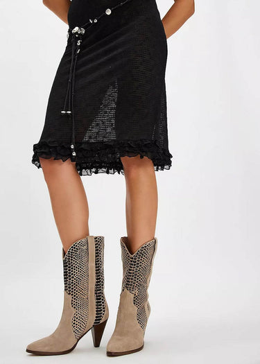 Eine Nahaufnahme von Damen-Cowboystiefeln mit Federabsatz von Free People, die mit einem schwarzen Rock gestylt werden.