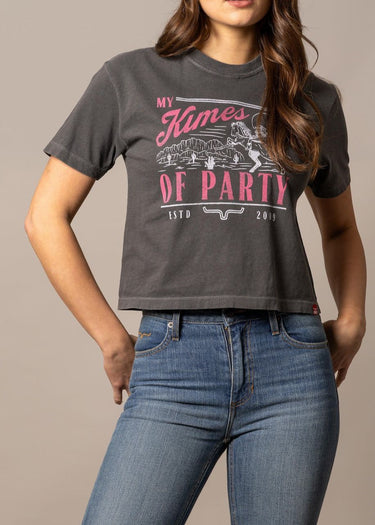 Woman wearing a cropped T-shirt donna Kimes Ranch with cowgirl graphics and denim jeans.